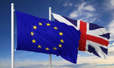 44876121 - waving flags of eu and uk on flagpole, on blue sky background.